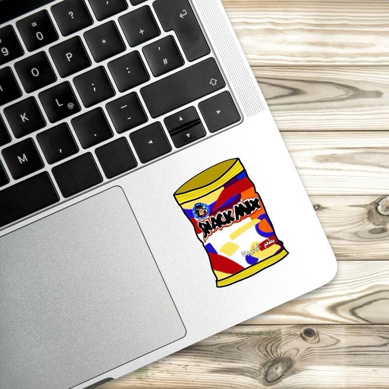 Laptop with a colorful 'Snack Mix' sticker on a wooden surface
