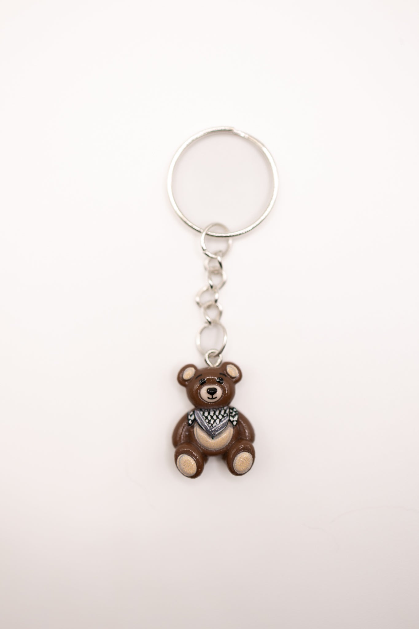 Keychain with a bear charm and keffiyeh scarf on a white background