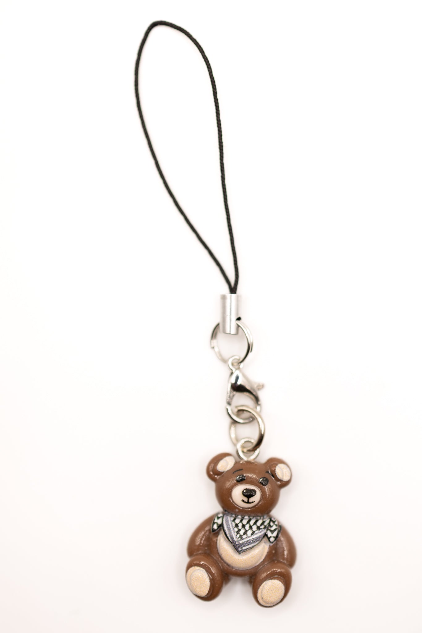 Brown keffiyeh teddy bear phone charm with a black strap on a white background