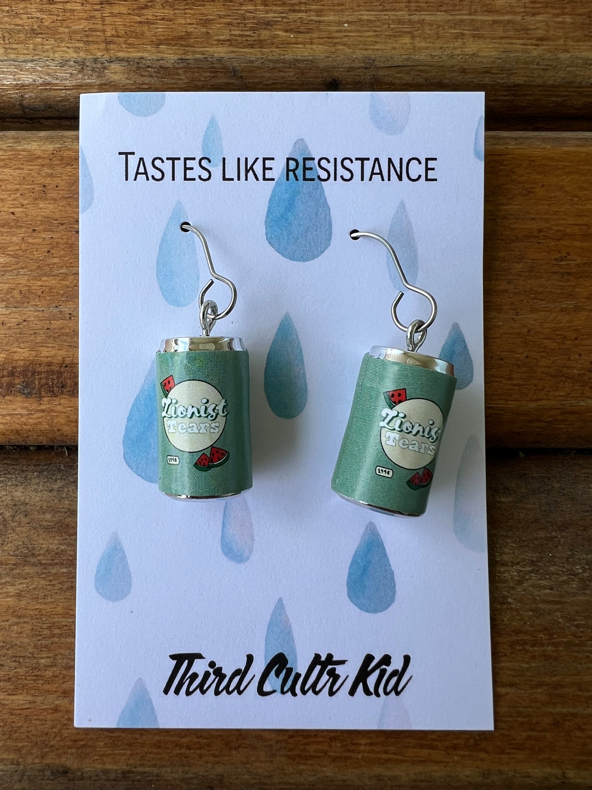 Earrings on a branded card with 'Tastes Like Resistance' text.