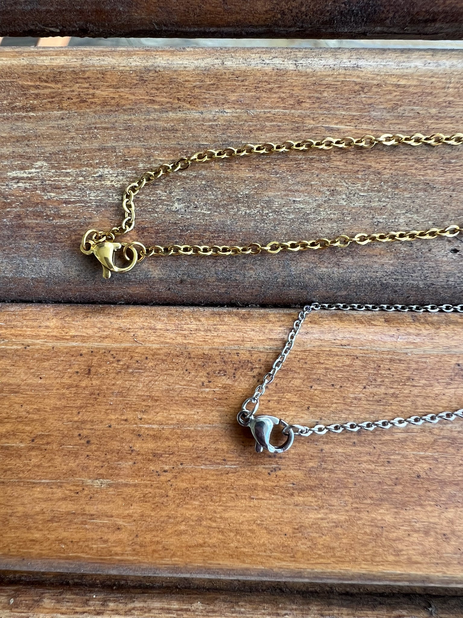 Two gold necklaces on a wooden surface