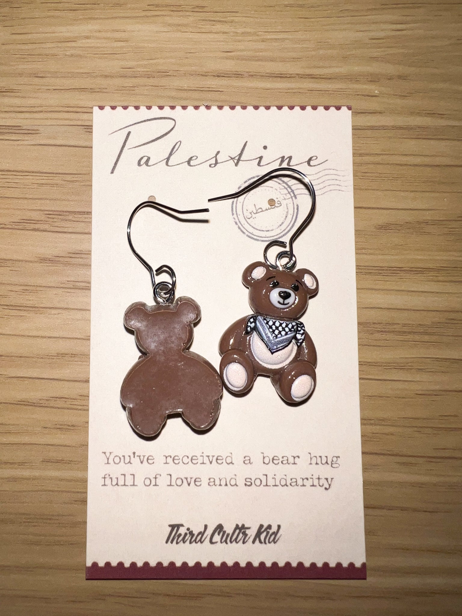 Teddy bear keychain on a card with text on a wooden surface