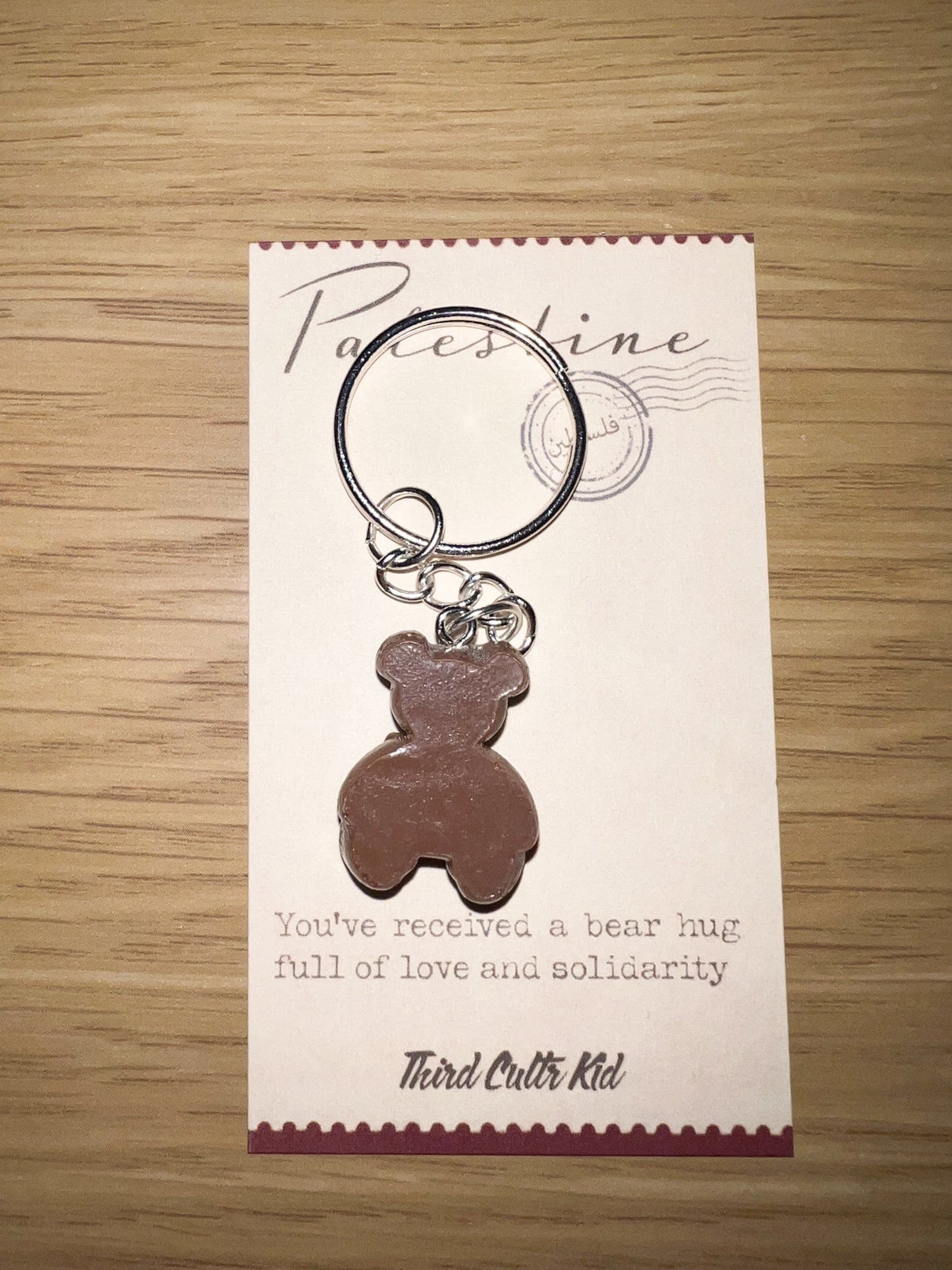 Keychain with bear design on a card with text on a wooden surface