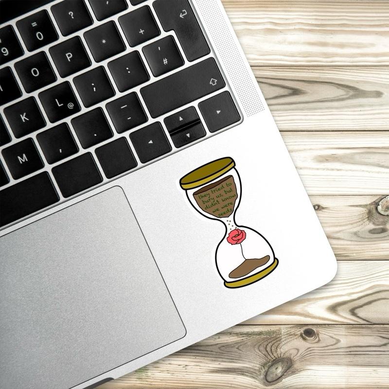 Laptop with a sticker of an hourglass on a wooden surface