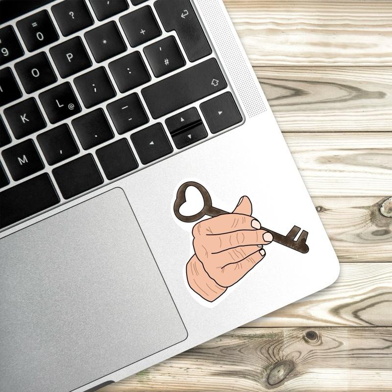 Laptop with a key and hand design on a wooden surface