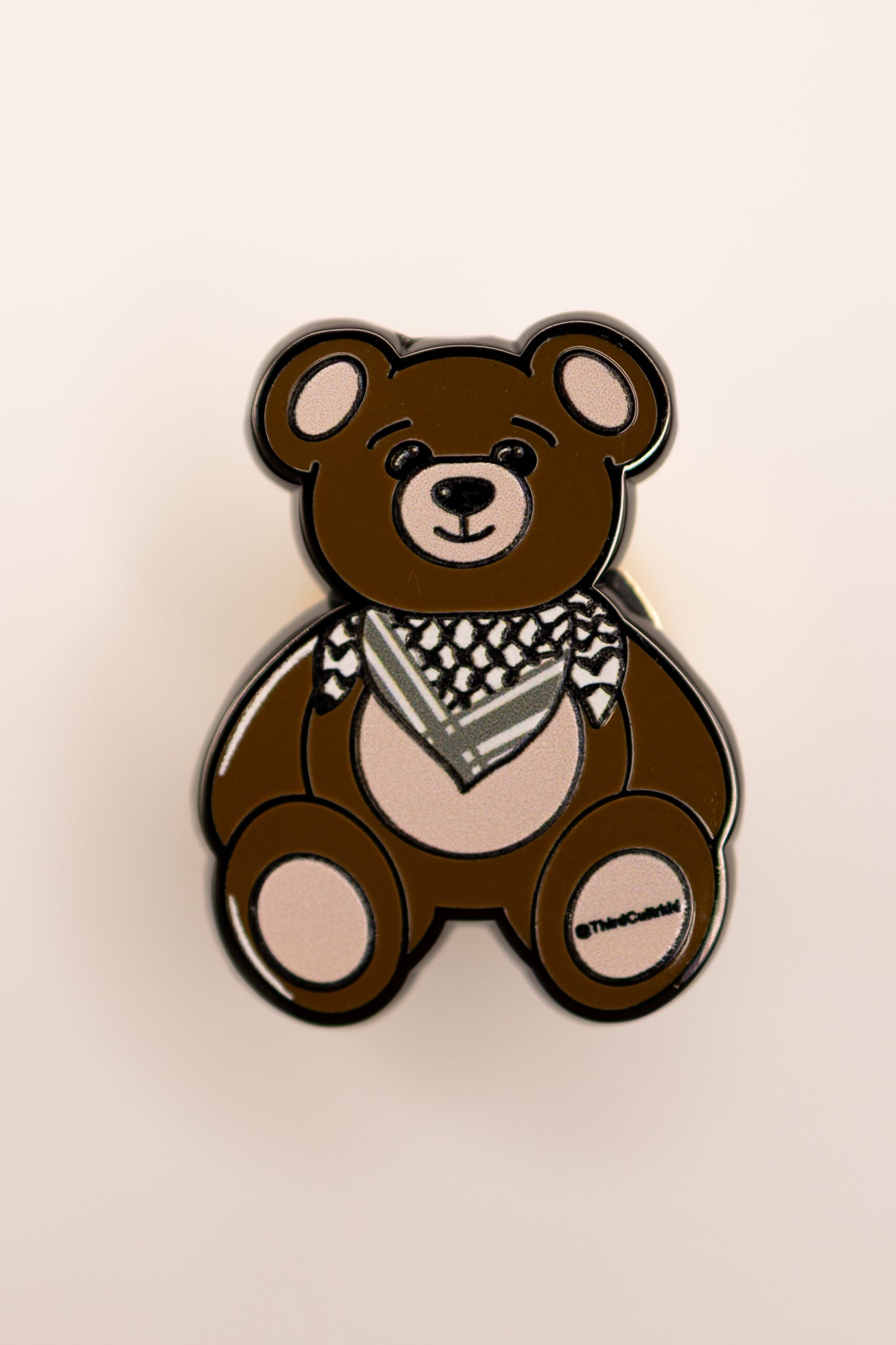 Brown teddy bear with a keffiyeh palestine scarf on a beige background