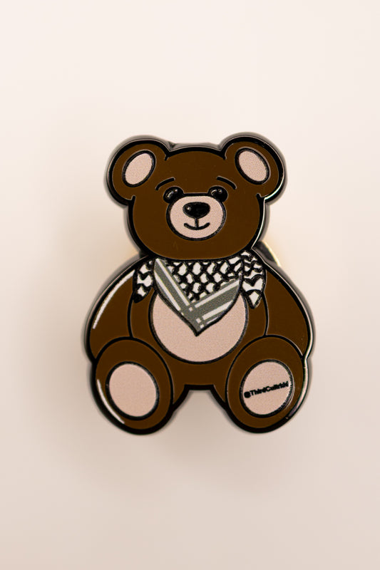 Brown teddy bear with a keffiyeh palestine scarf on a beige background