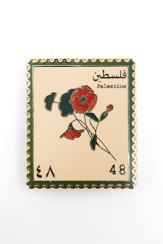 Pin with a design resembling a vintage Palestinian postage stamp featuring flowers and text.