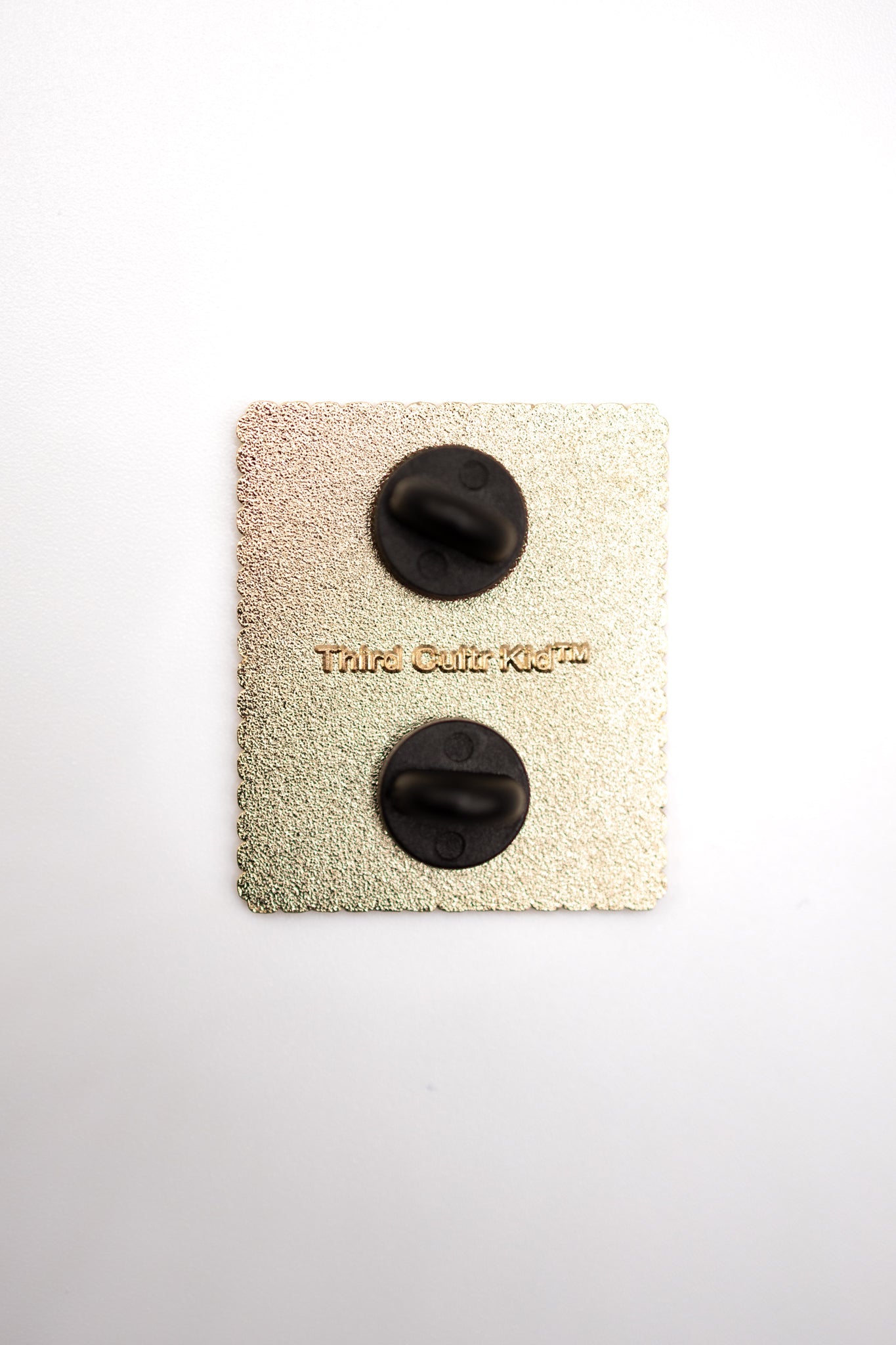 Back of pin with rubber clasps with a design resembling a vintage Palestinian postage stamp featuring flowers and text.