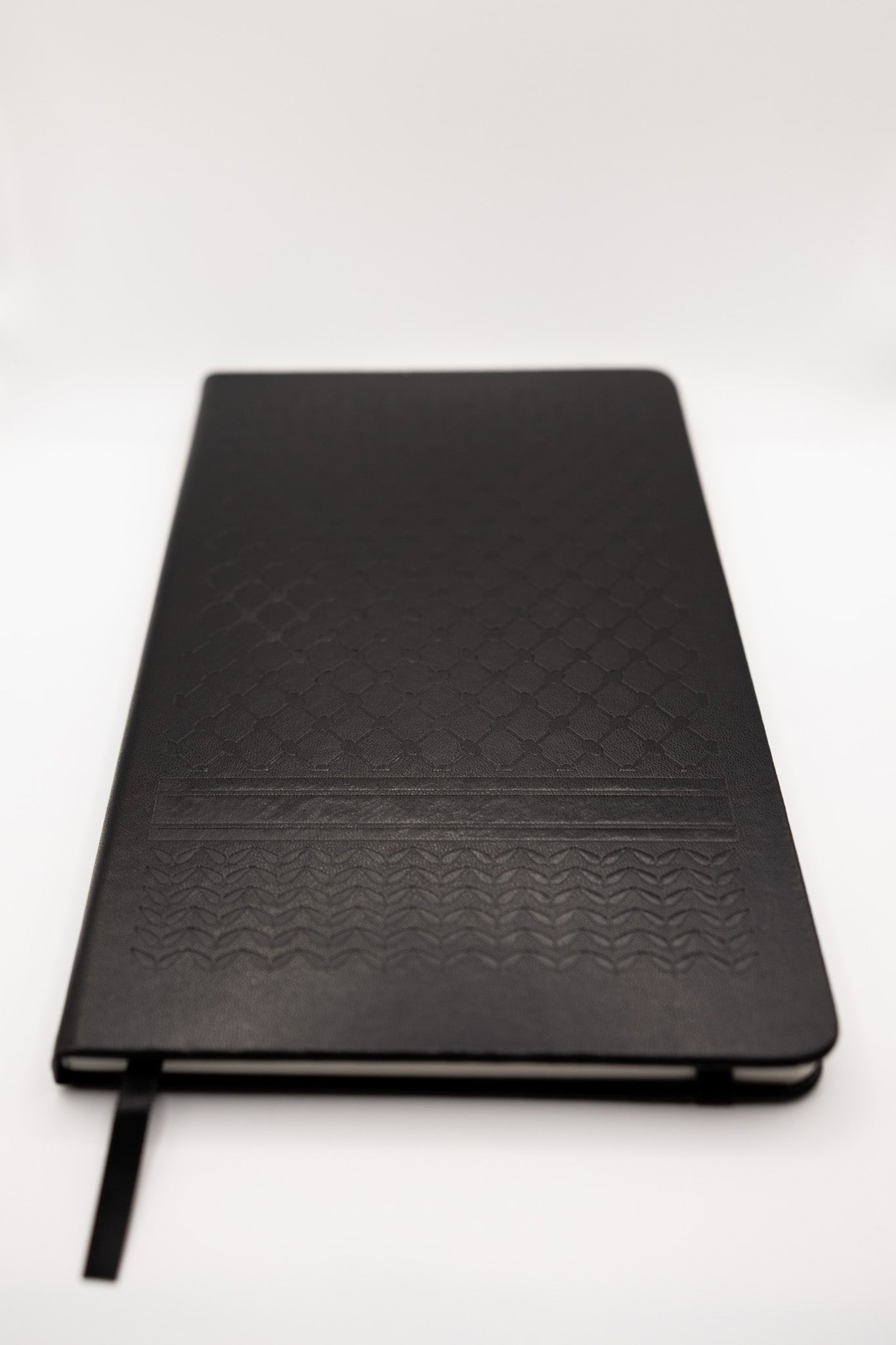 Black notebook with keffiyeh textured cover on a white background