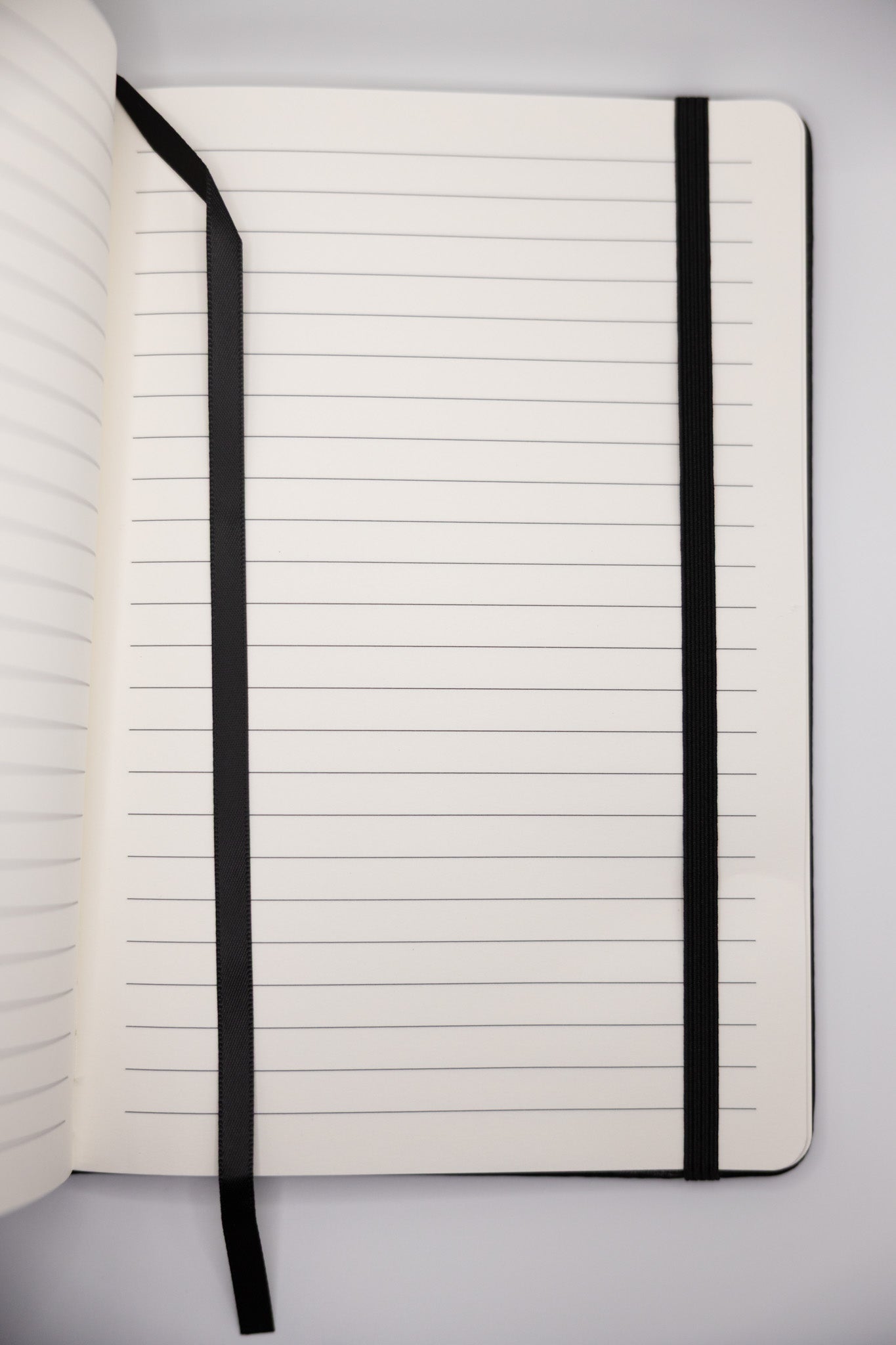 Open notebook with lined pages and black binding on a light gray background