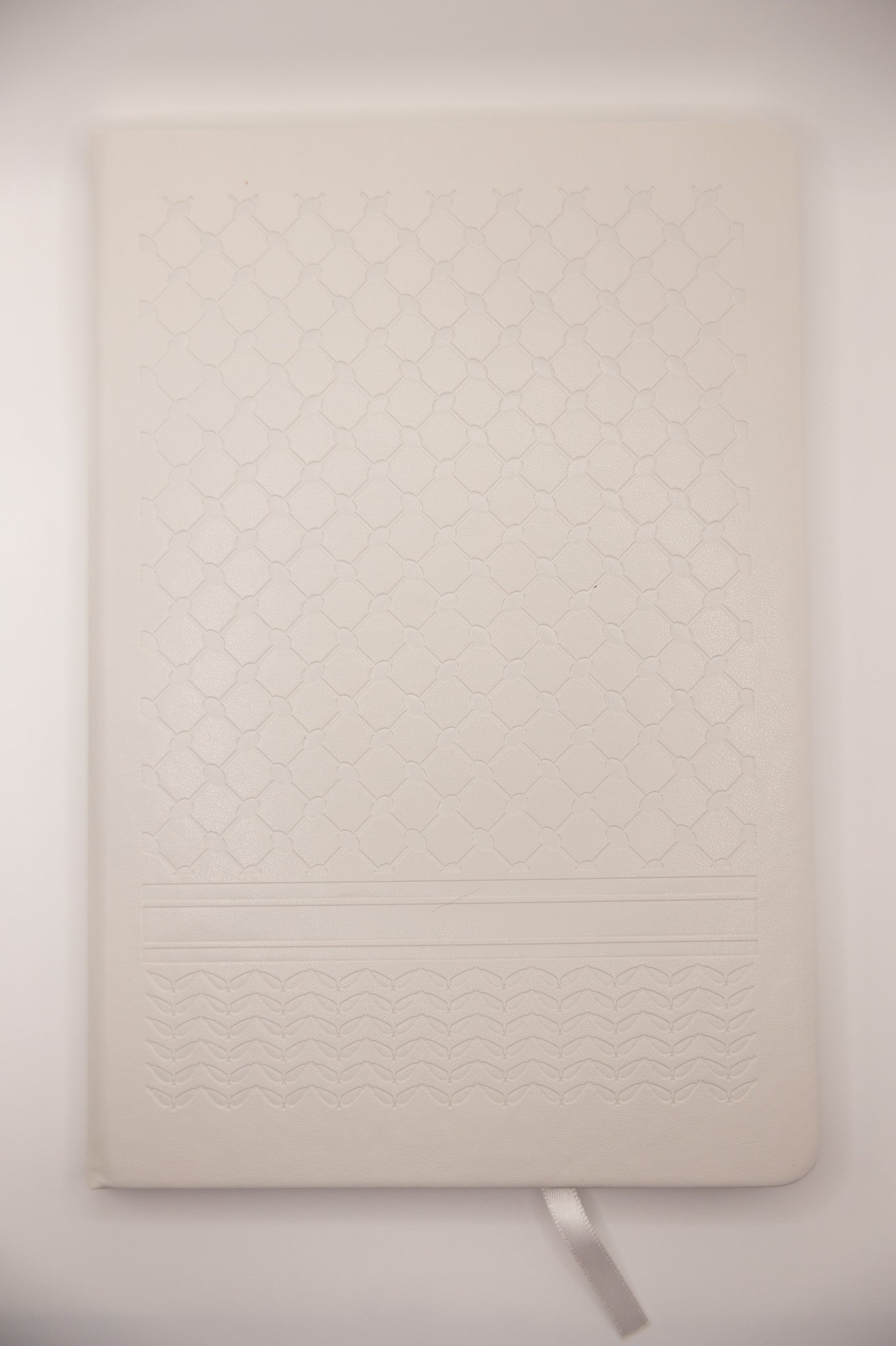 white keffiyeh textured notebook on a light gray background