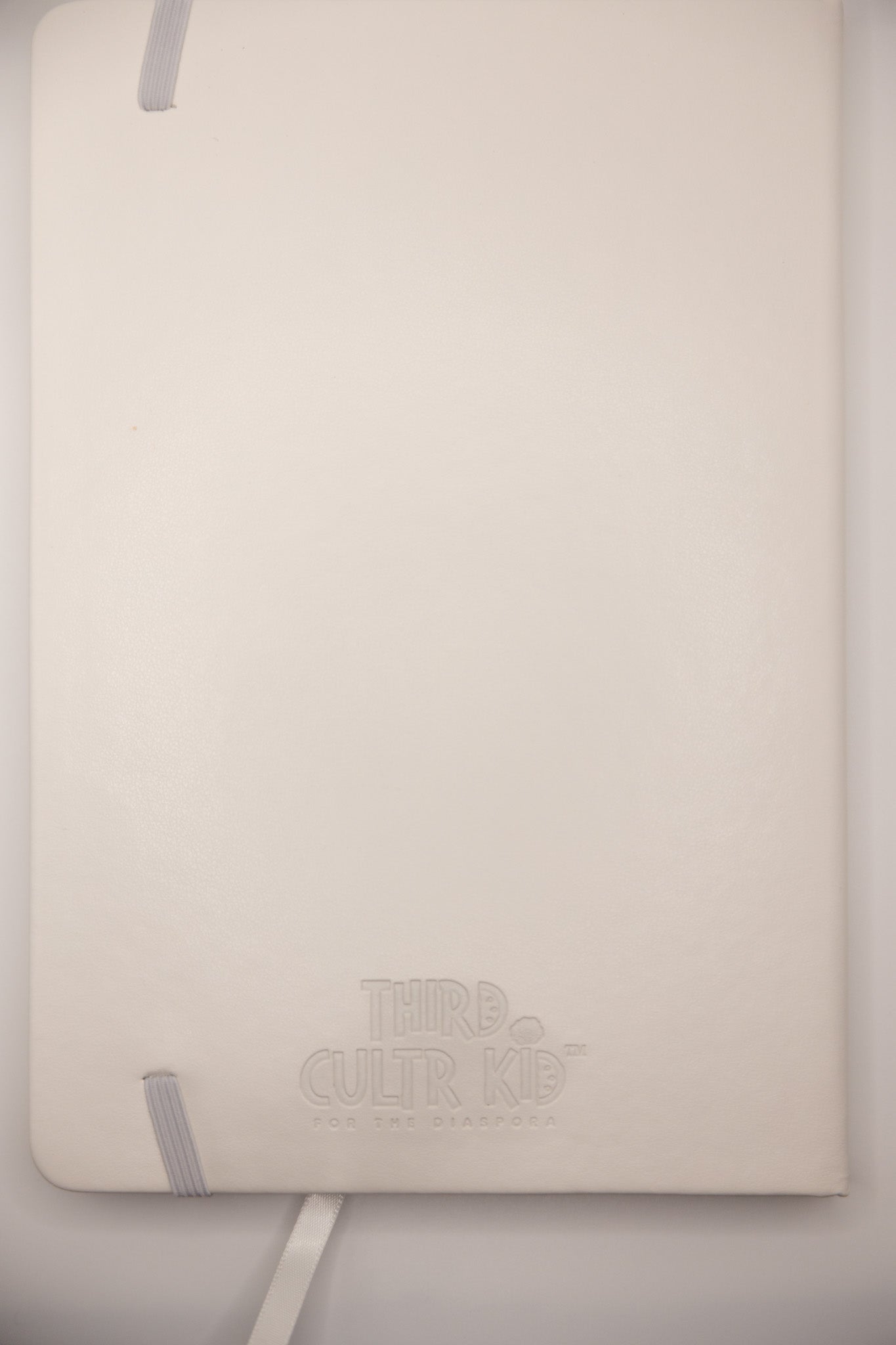 White notebook keffiyeh embossed on it, on a light gray background