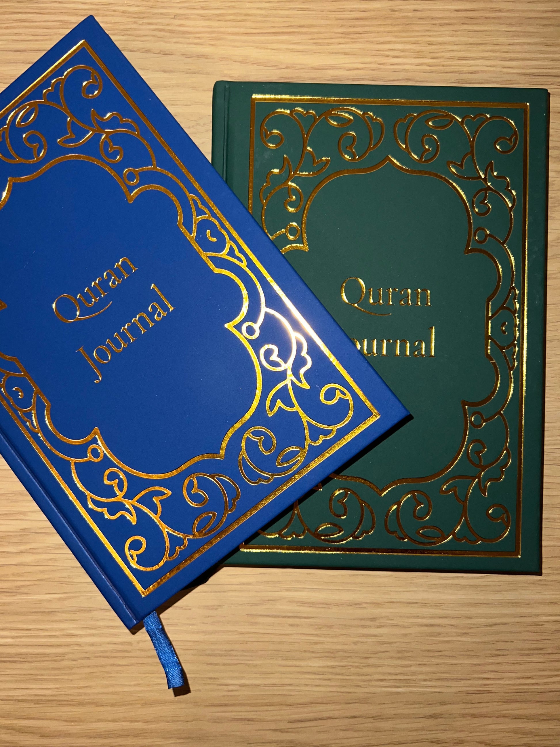Blue and green Quran journals with ornate designs on a wooden surface