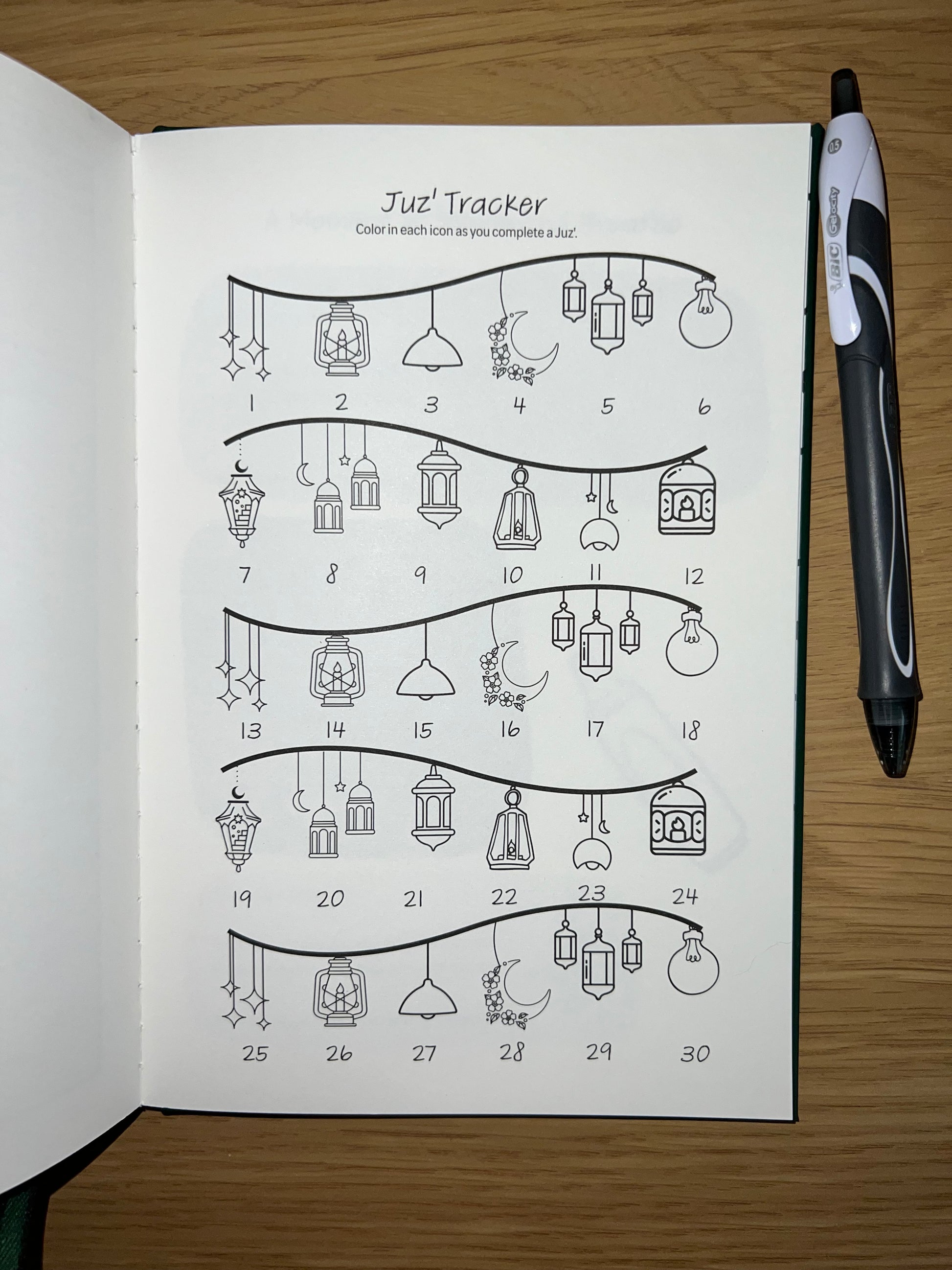 Open book with a diagram and pen on a wooden surface a Quran juzu tracker to track each chapter of the Quran 