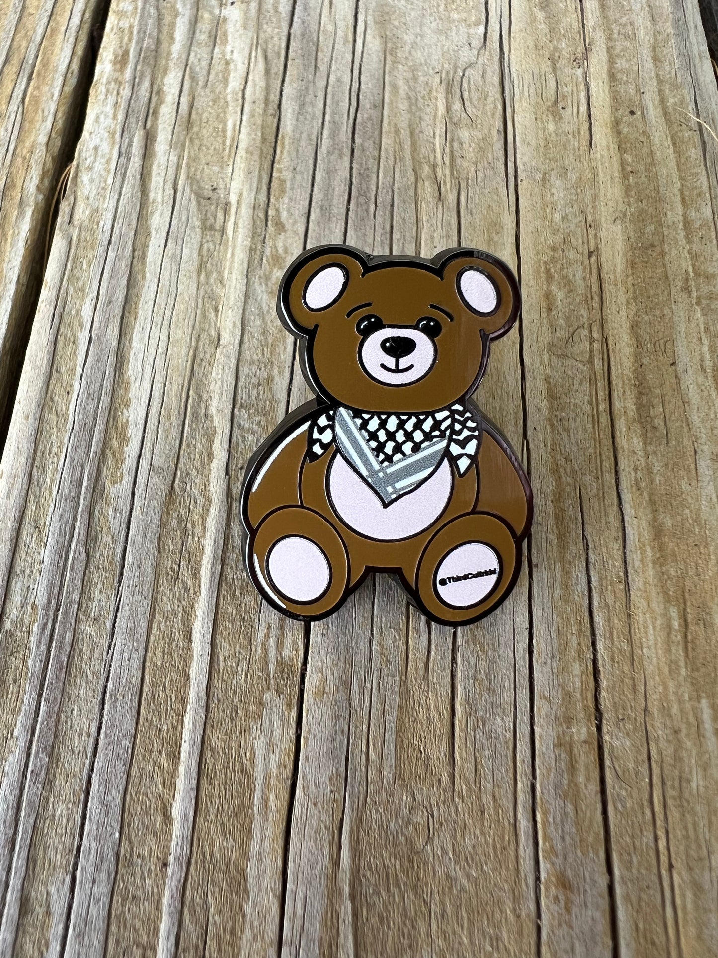 Brown teddy bear with a bandana on a wooden surface